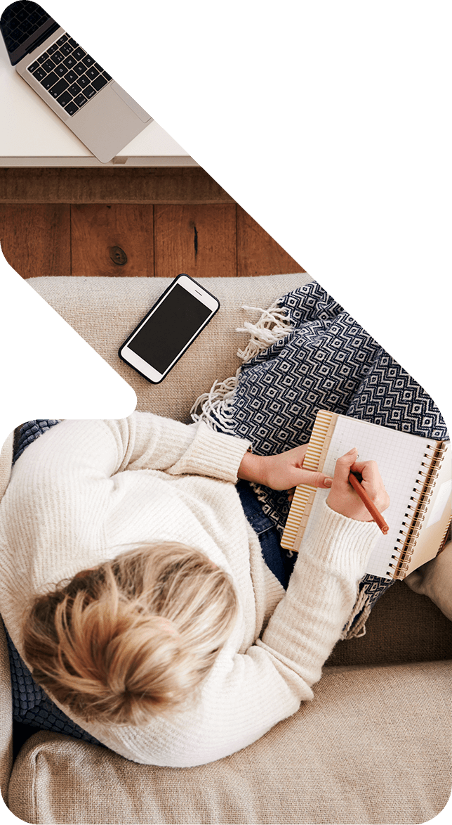 Image showing an aerial view of a woman on her couch with a notepad and phone