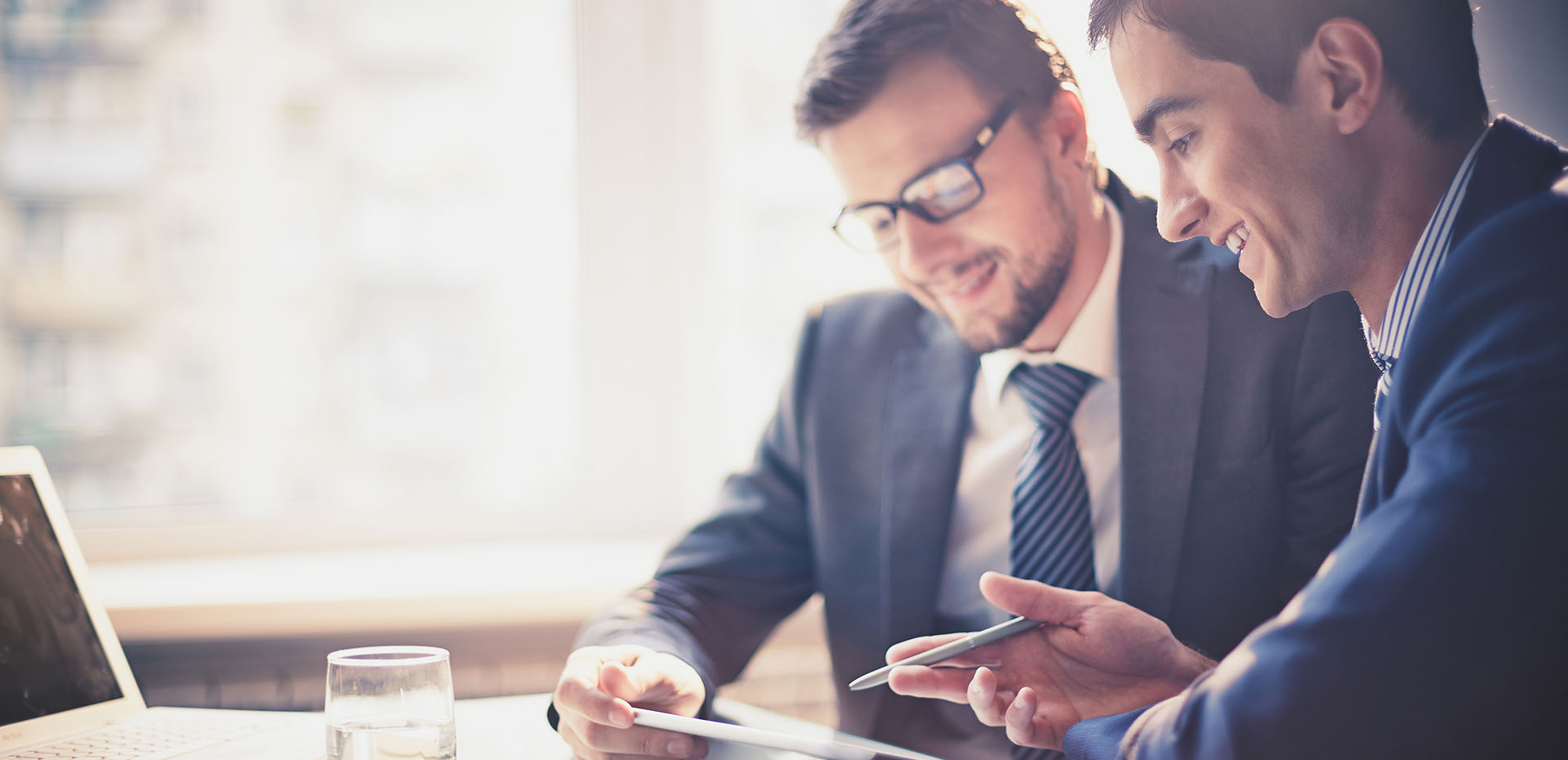 Image showing 2 smiling businessmen looking at a tablet together