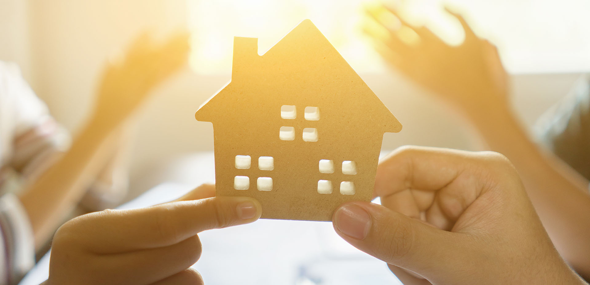 Image showing a close up of a model house being held up by different people